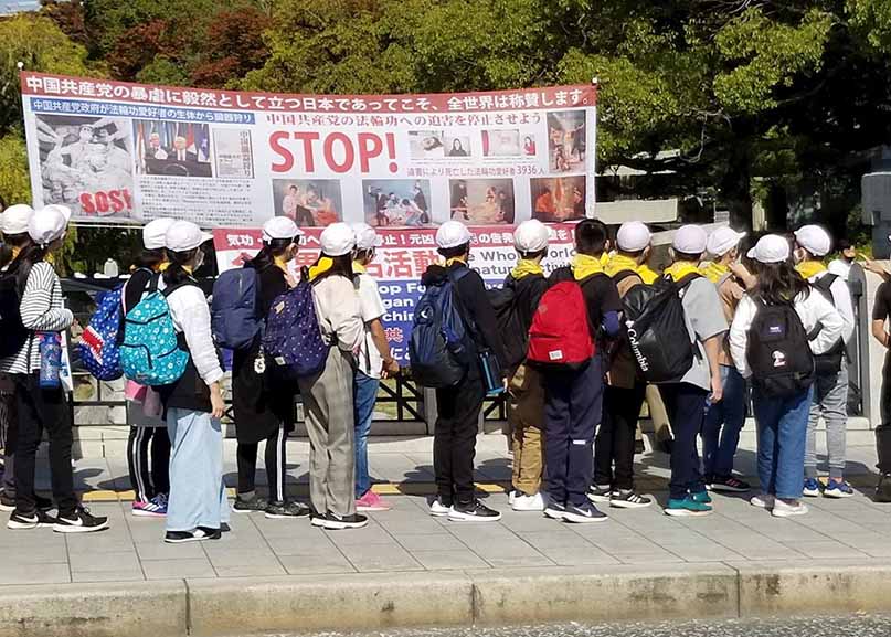Image for article Хиросима, Япония. Туристы и местные жители знакомятся с Фалунь Дафа в Мемориальном парке мира